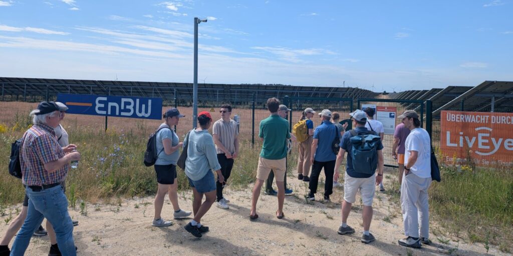 Die Gruppe Betritt den normalerweise nicht zugänglichen Bereich des Solarparks Weesow-Willmersdorf. So können die Teilnehmenden sich die Technik, die Solarpaneele und Wechselrichter von nahem angeschaut werden.